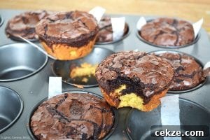 Deep Dish Brookies with a bite out of one on top of a muffin pan. with more deep dish brookies in the background in the muffin pan