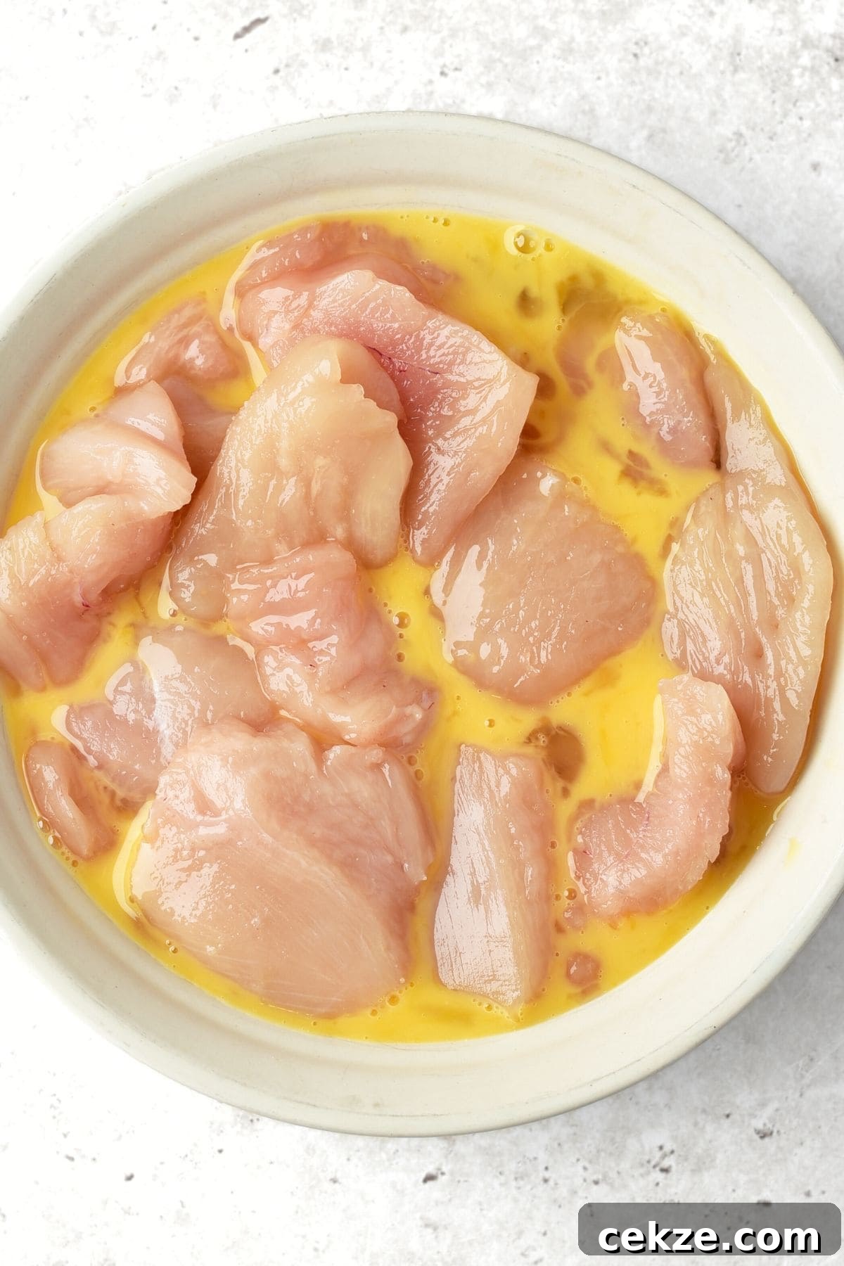 Gluten-Free Dairy-Free Homemade Turkey Nuggets Recipe 2 Turkey pieces in bowl of beaten egg.