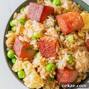 bowl of spam fried rice with crispy cubes of spam, eggs, green peas, and sesame seeds