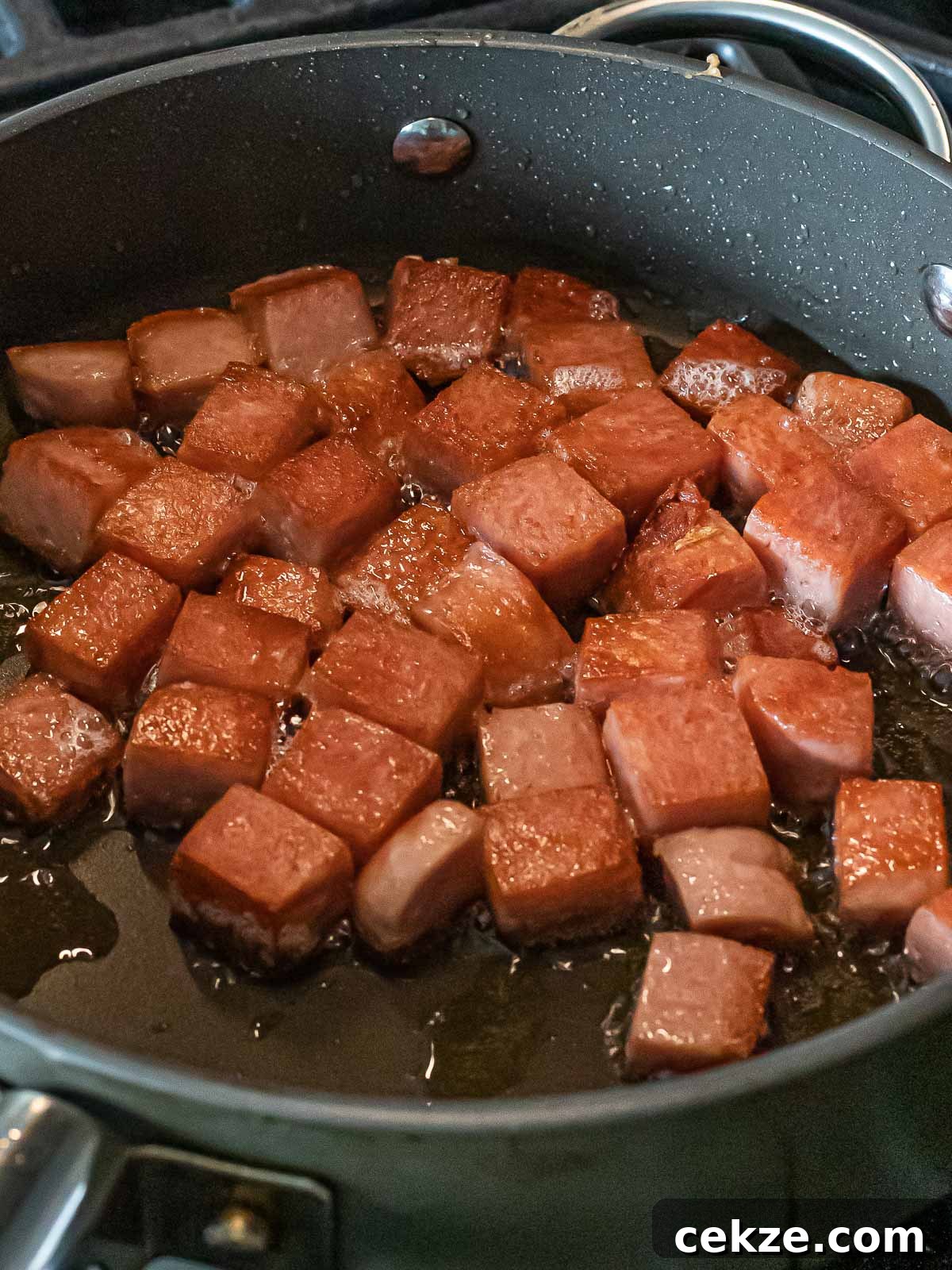 cubes of spam frying in a nonstick pan