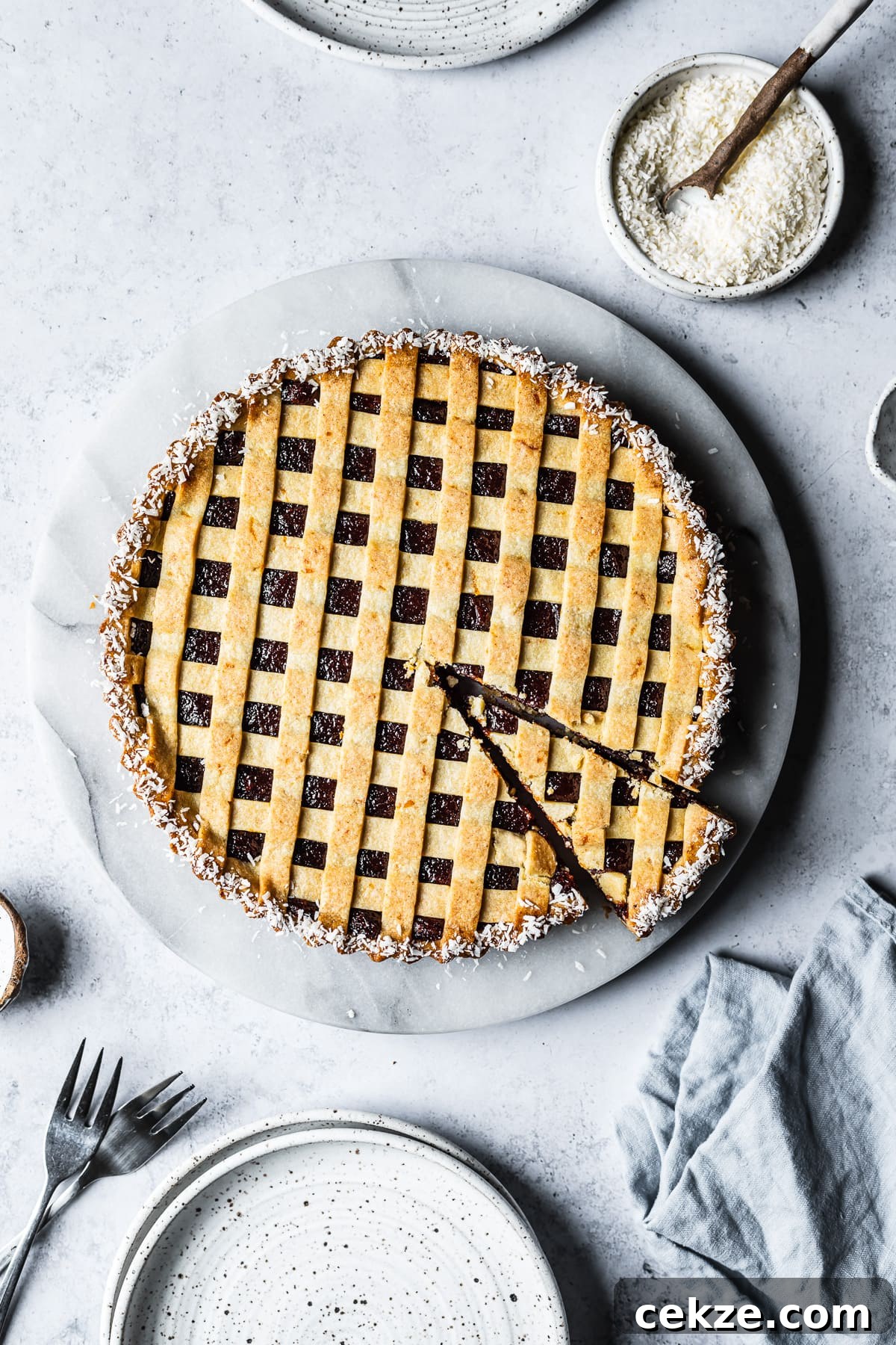 A baked tart with thin lattice on top and a border of dessicated coconut. 