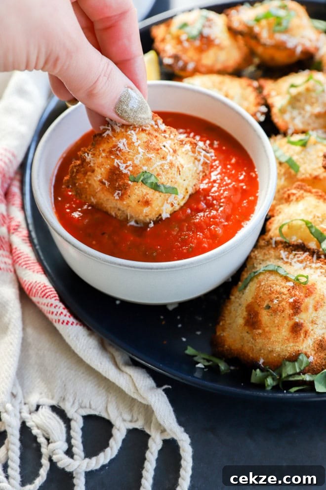 hand dipping the ravioli into sauce with fresh herbs