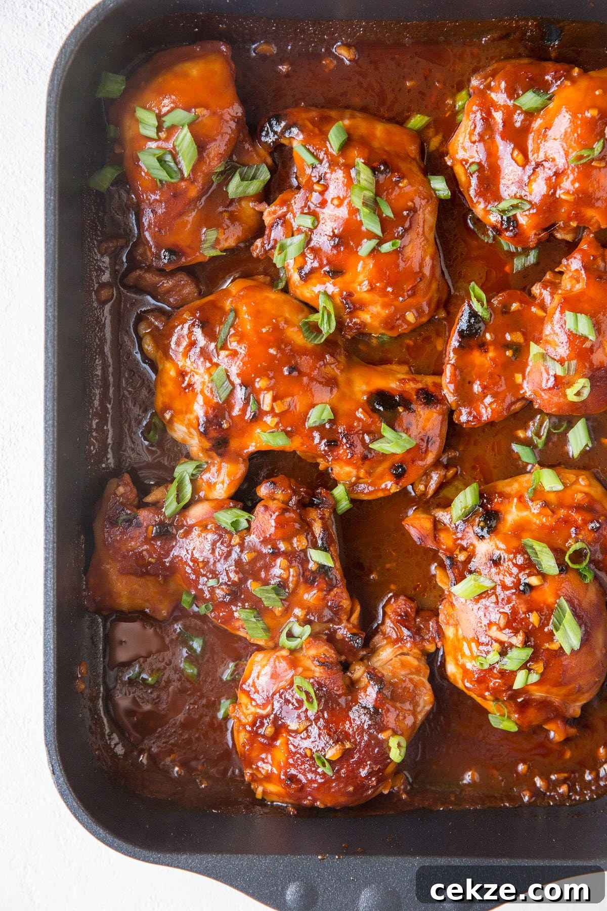 Top Chicken Thigh Recipes for Flavorful Weeknight Dinners 18 Casserole dish with BBQ chicken all sauced up with green onions sprinkled on top