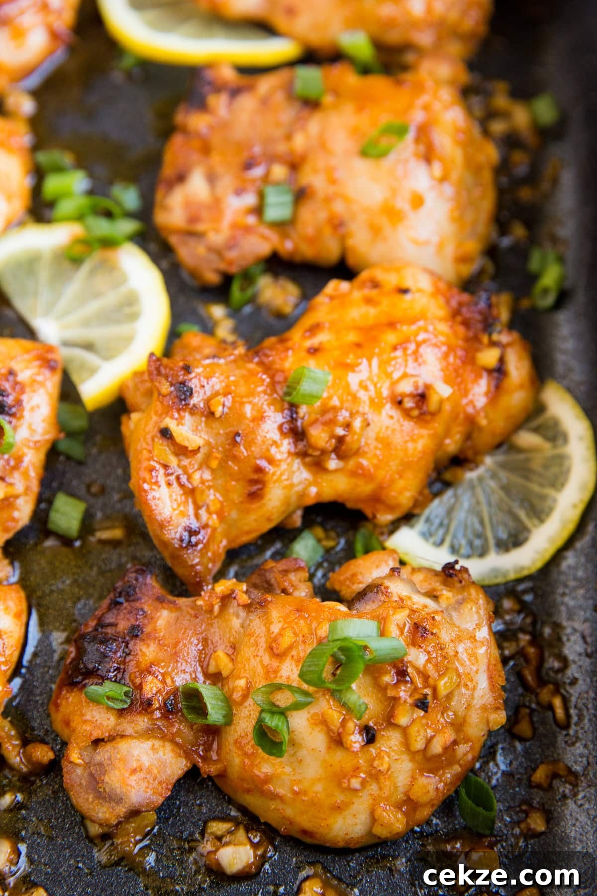 Top Chicken Thigh Recipes for Flavorful Weeknight Dinners 19 Casserole dish with baked boneless lemon garlic chicken thighs with sliced of lemon and green onion.