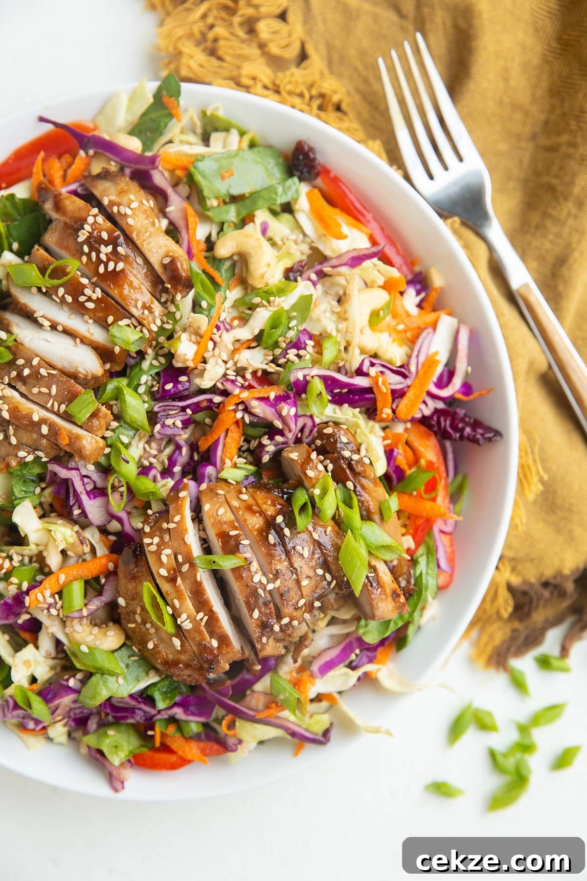 Top Chicken Thigh Recipes for Flavorful Weeknight Dinners 22 Big white bowl with chopped salad and sliced chicken on top.