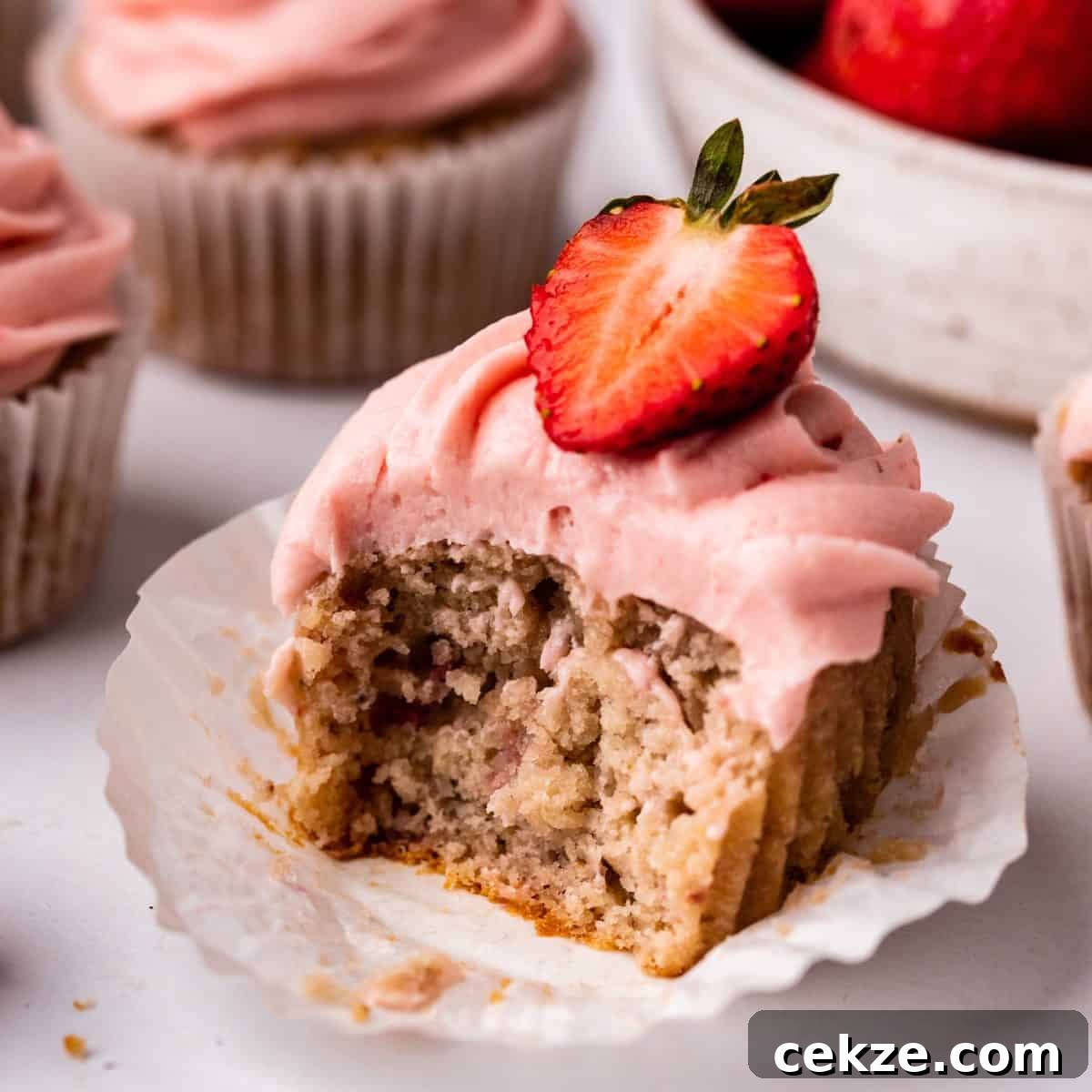 a frosted Strawberry Cupcake with a bite taken out of it