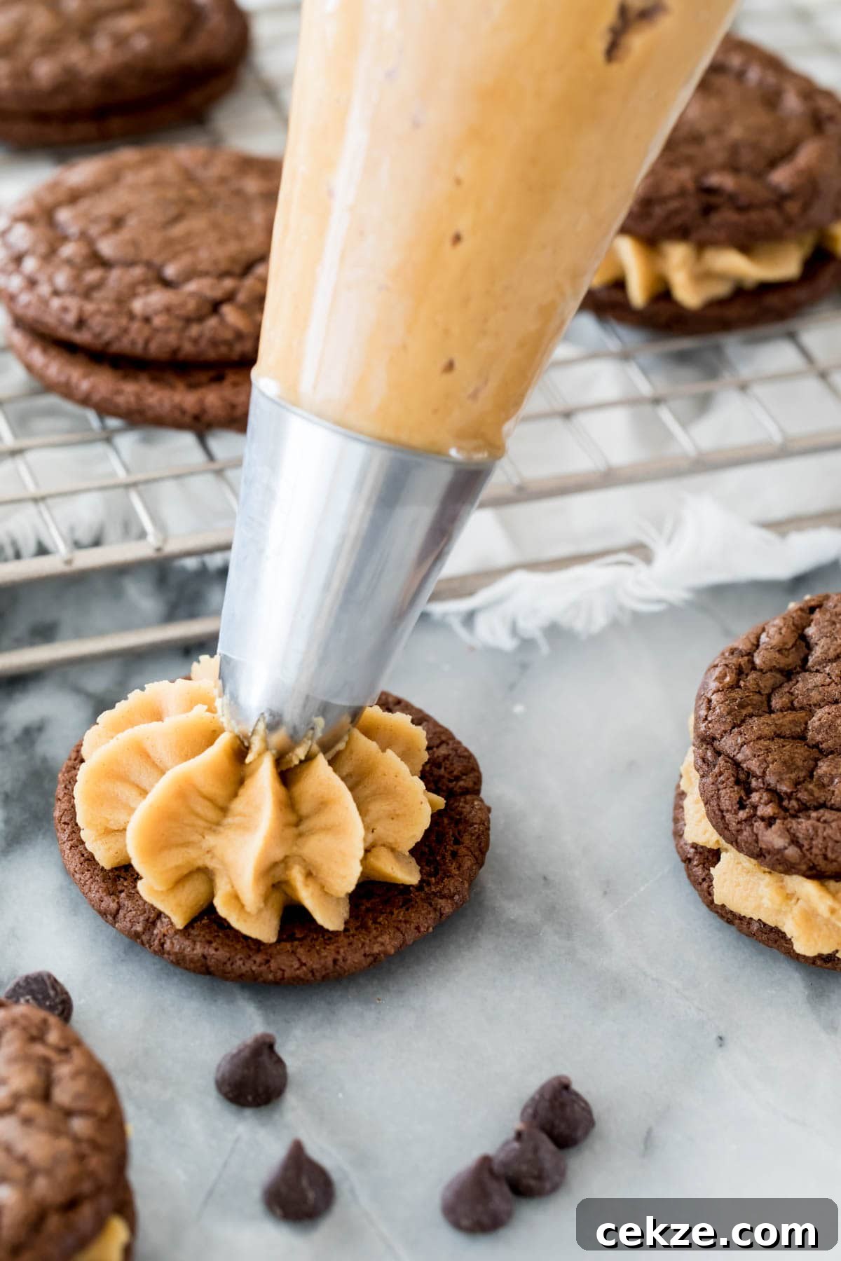 piping peanut butter frosting on chocolate cookie