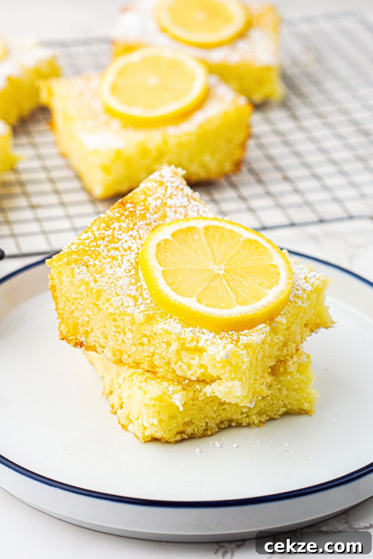 2-Ingredient Lemon Bars Recipe — Quick Tangy Dessert 2 Bright yellow lemon bars stacked on a small white plate with a slice of lemon on top.