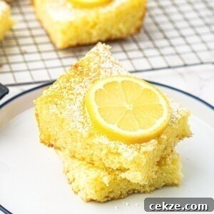 2-Ingredient Lemon Bars Recipe — Quick Tangy Dessert 9 Bright yellow lemon bars stacked on a small white plate with a slice of lemon on top.