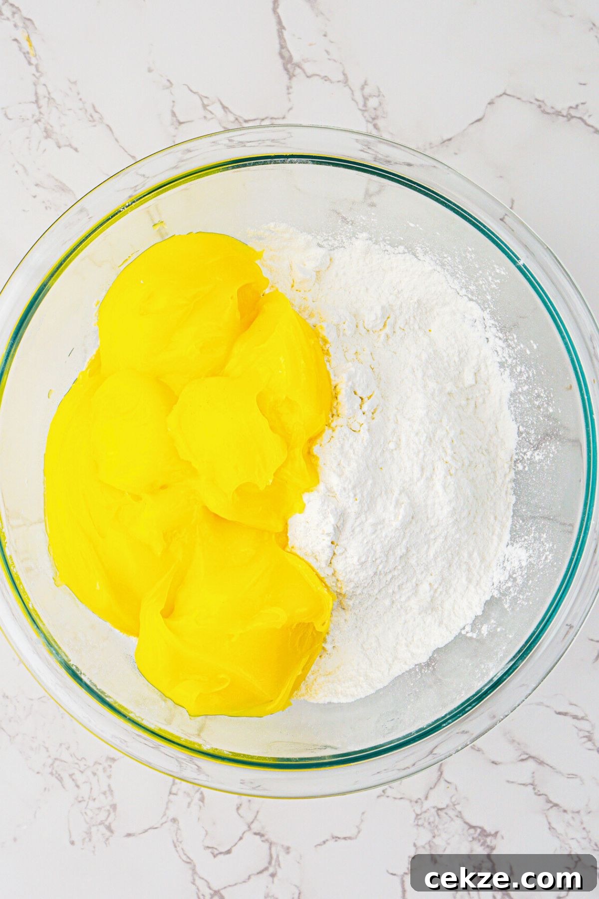 2-Ingredient Lemon Bars Recipe — Quick Tangy Dessert 4 Cake mix and lemon pie filling being mixed together in a clear glass bowl.