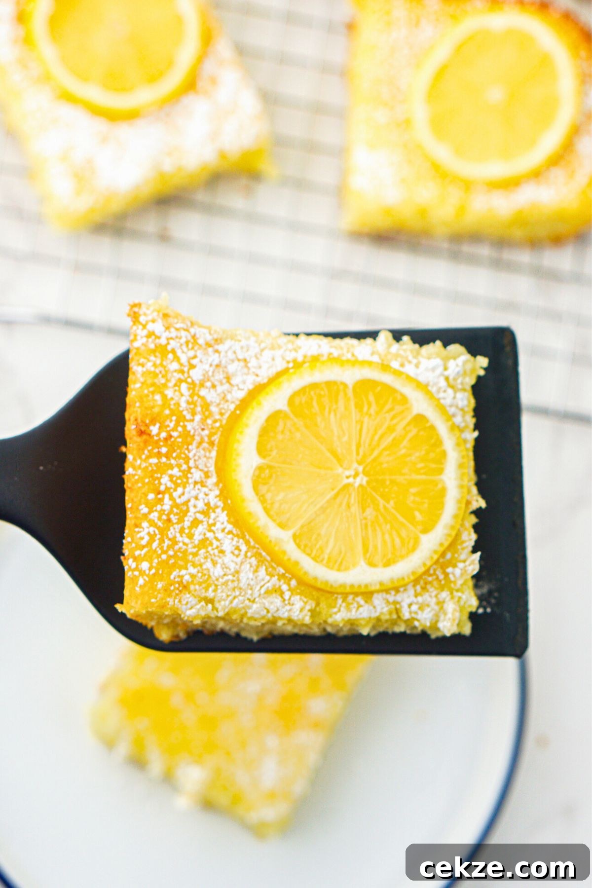 2-Ingredient Lemon Bars Recipe — Quick Tangy Dessert 8 Bright yellow lemon bars after baking, with one being lifted to serve on a spatula.