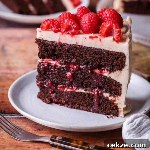 Slice of Chocolate Raspberry Cake on a plate. Moist chocolate sponge, raspberry jam squidging out of the filling.