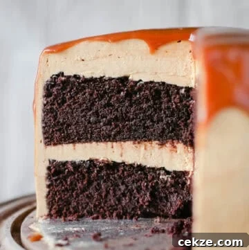 salted caramel chocolate cake on a wooden cake stand.