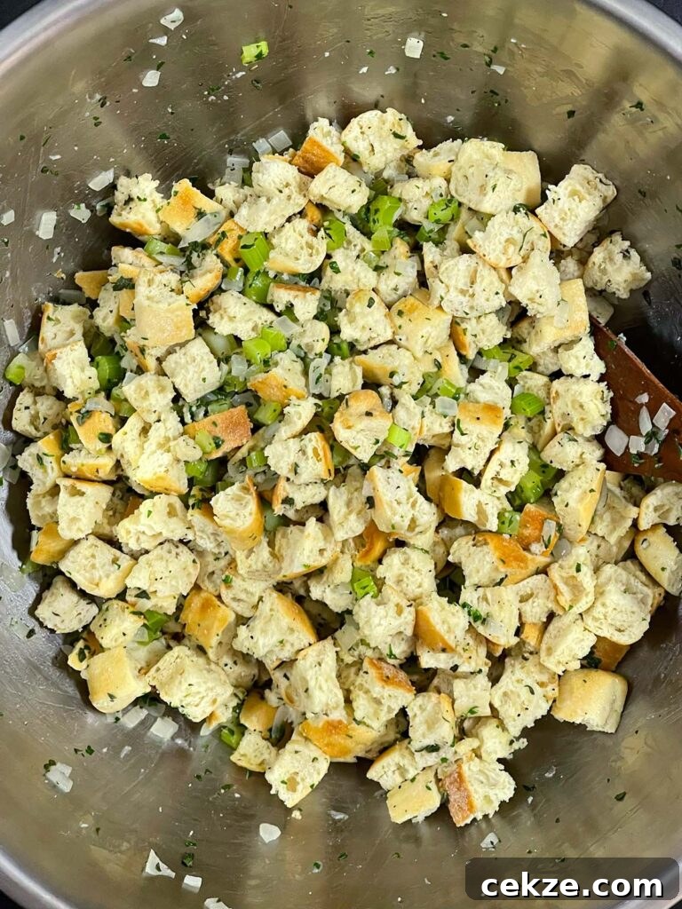 Stuffing mixture of bread, vegetables, and herbs fully combined in a bowl.