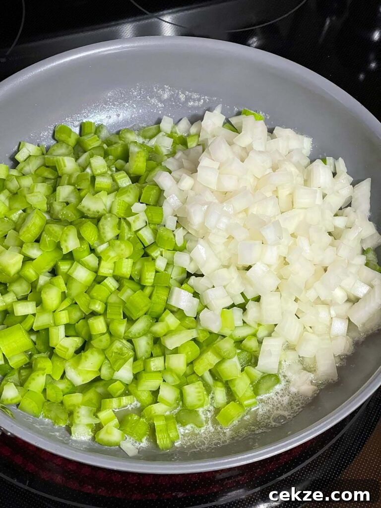 Diced onion and celery cooking in butter in a skillet.
