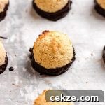 Chewy Coconut Macaroons Recipe with Golden Crispy Tops 15 Coconut macaroons dipped in chocolate on parchment paper.