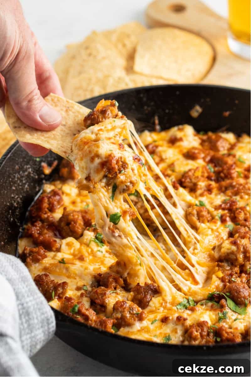chip with a bite of chorizo queso fundido with lots of melted cheese