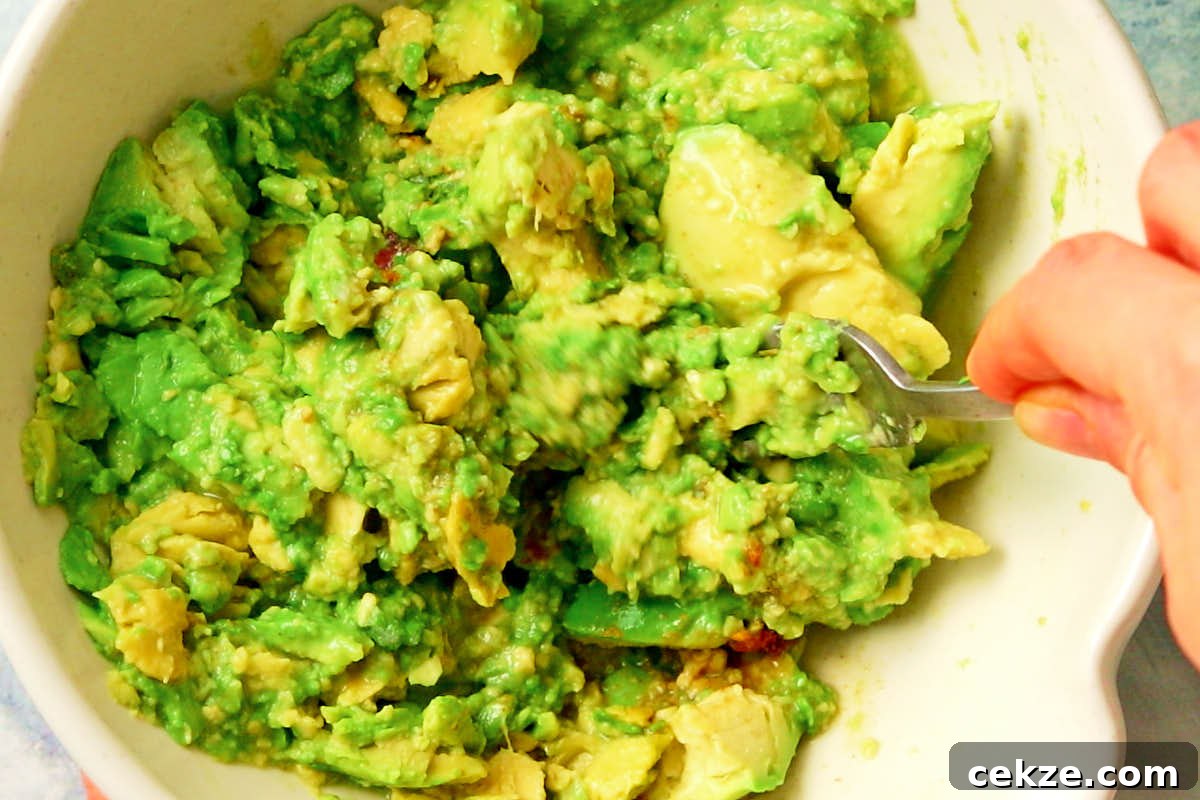 Mashing avocado with a fork to make vegan guacamole.