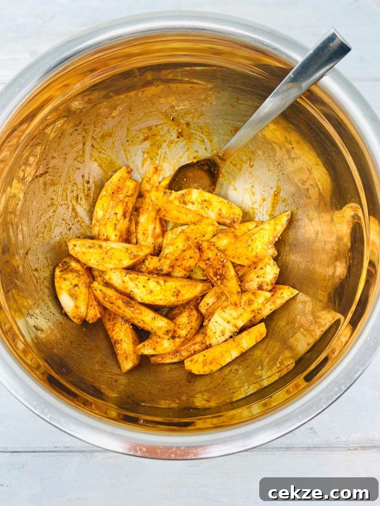 raw potato wedges being seasoned with peri peri seasoning and olive oil