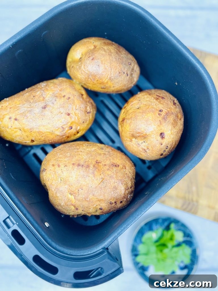 jacket potatoes in air fryer basket - cooked, crispy and golden