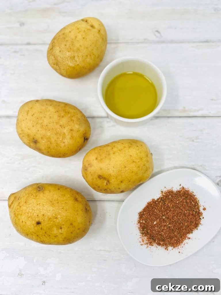 four potatoes, cup of olive oil and saucer of peri peri seasoning on a white table
