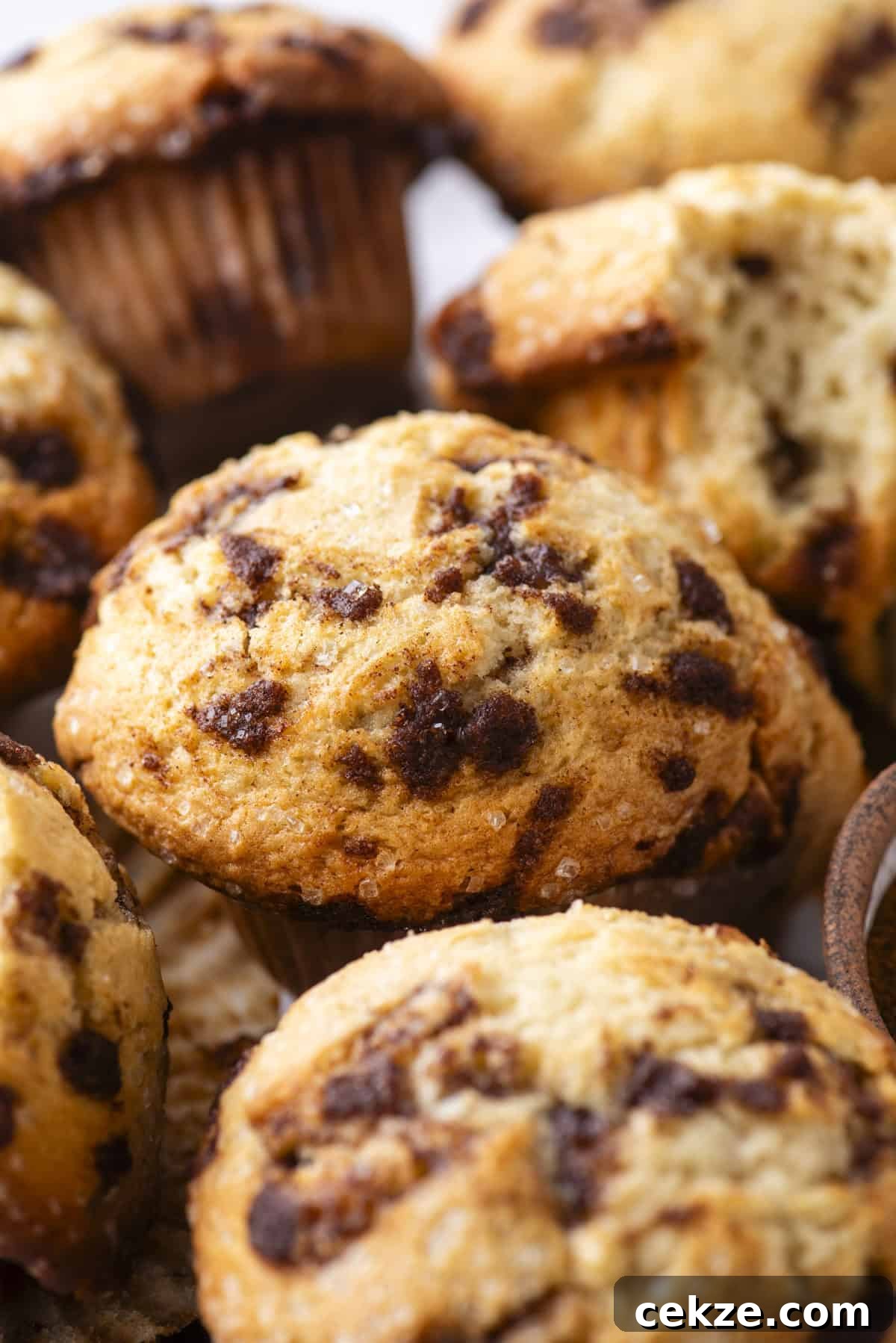 Cinnamon Baking Chips: Flavorful Mix-Ins for Cookies & Muffins 4 Close-up of cinnamon chip muffins with golden, slightly crisp tops and visible cinnamon pieces, one muffin partially broken open to show the soft, moist inside.