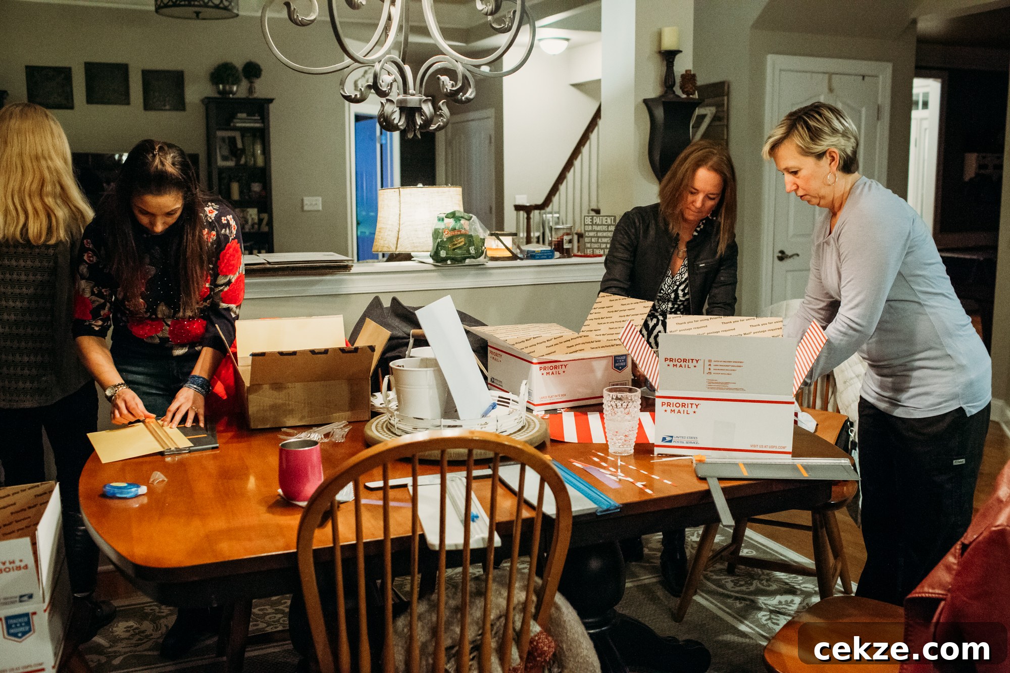Moms working on decorating post office mailing boxes around a kitchen table