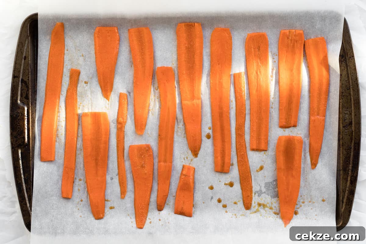 Crispy Bacon-Roasted Carrots with Maple Glaze 7 carrots on a baking tray with parchment paper