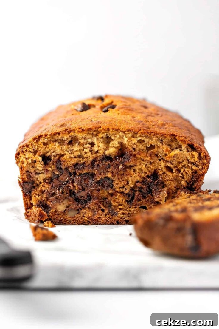 A ricotta banana bread loaf, cut in half, on a white marble serving board.
