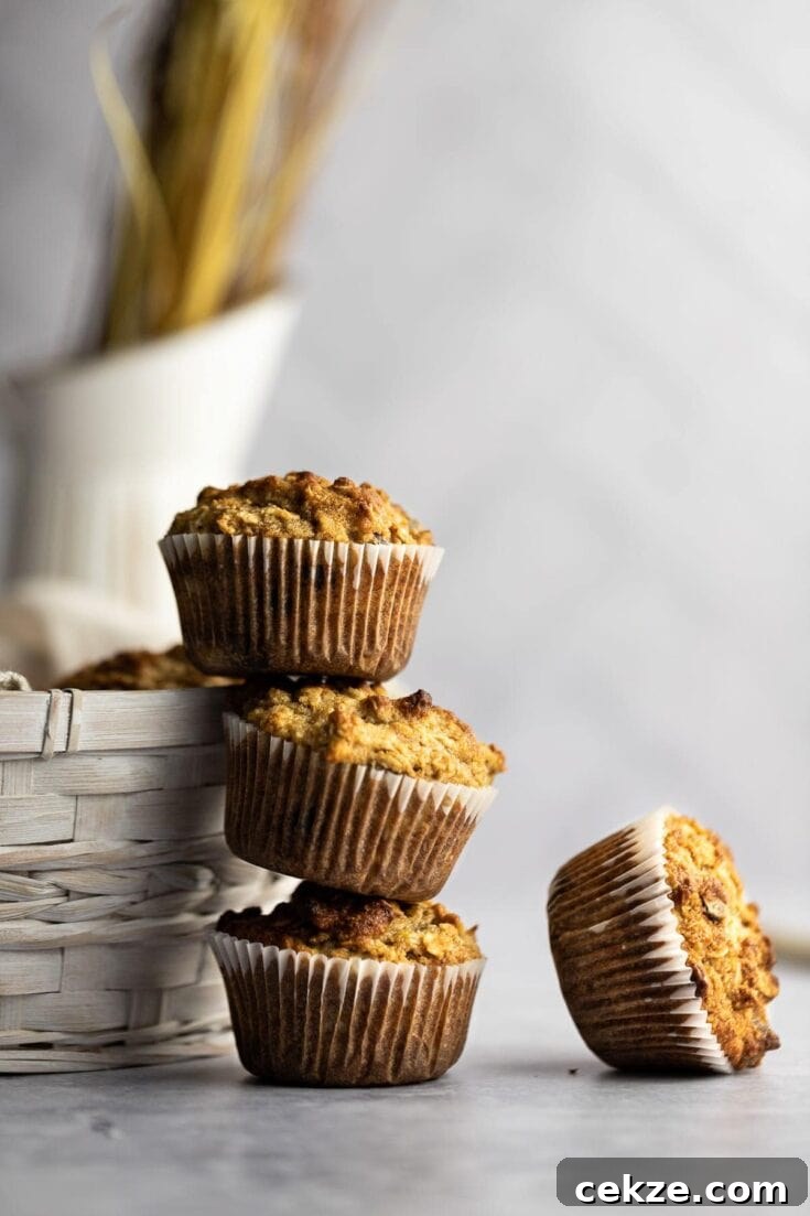Three banana almond flour muffins stacked on top of each other, leaning against a white woven basket.