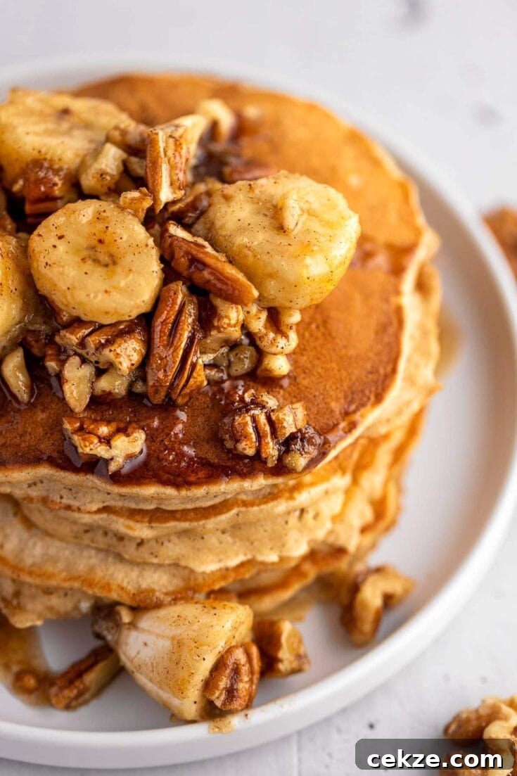 A stack of pancakes topped in bananas foster sauce.