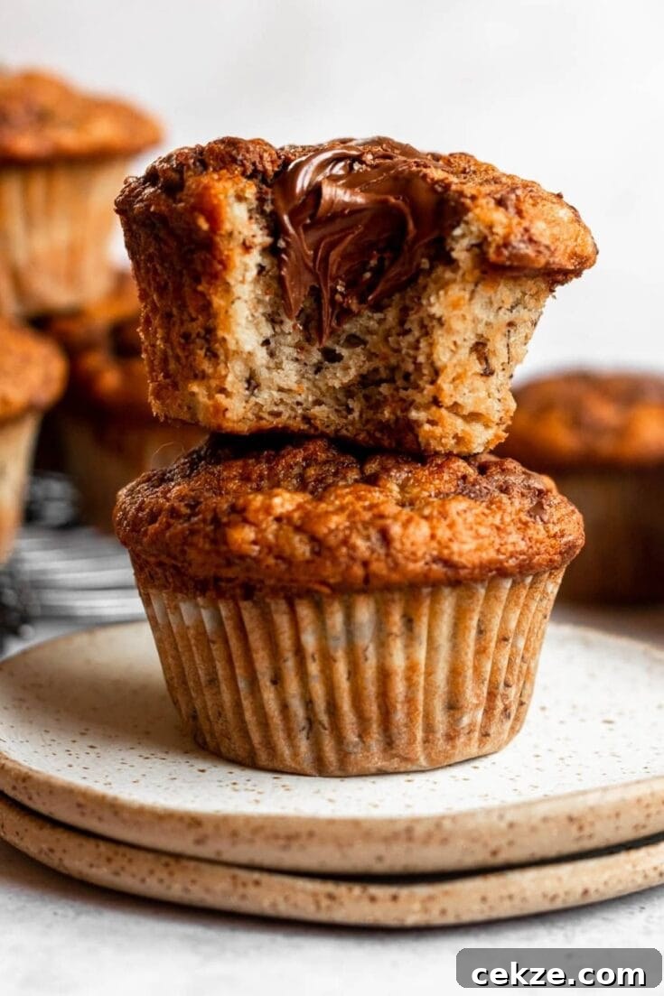 Two banana nutella muffins stacked on top of each other, with one missing a bite.