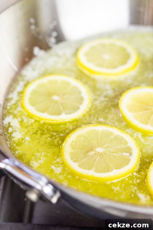 Garlic Butter Lemon Shrimp Recipe with Garlic-Parsley Sauce 6 Lemon slices in melted butter in skillet on stove top.
