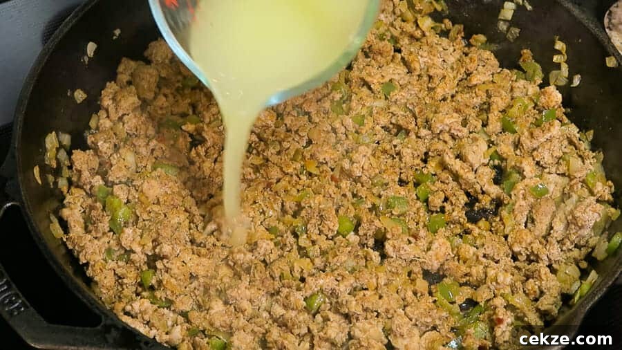 chicken broth being added to the ground turkey