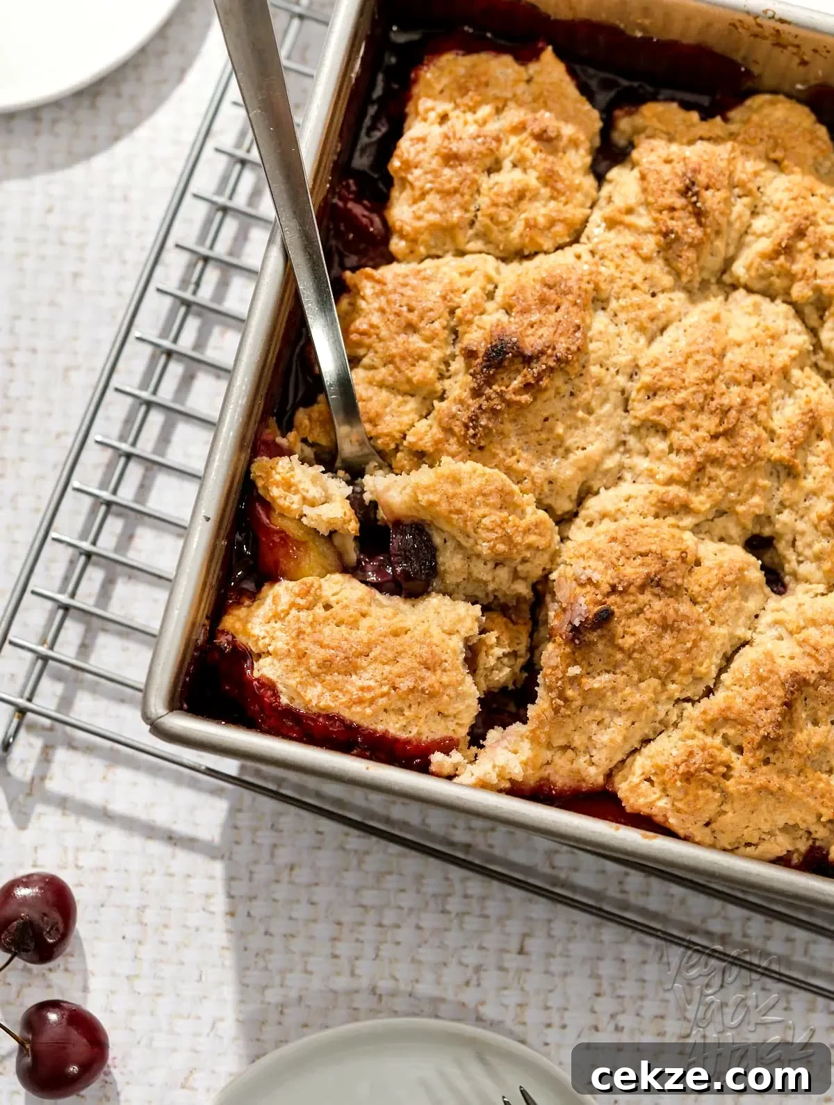 Square baking dish of fruit cobbler on a wire rack, on a white table cloth