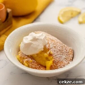 Baked Lemon Pudding in white bowl topped with whipped cream and powdered sugar.