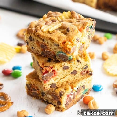 kitchen sink cookie bars recipe with potato chips, pretzels, caramel bits, m&m's, and chocolate chips shown with 3 bars in a stack