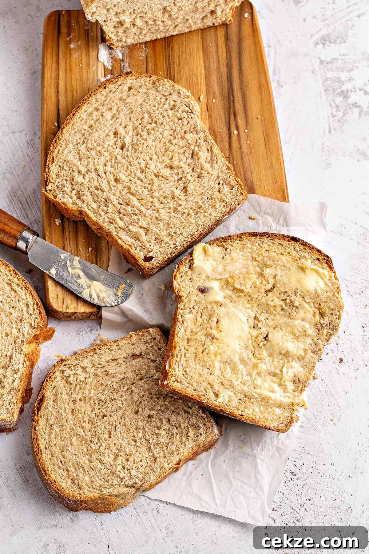 Homestyle Whole Wheat Sandwich Bread Recipe for Families 12 Several slices of whole wheat sandwich bread on a wooden board and white background.
