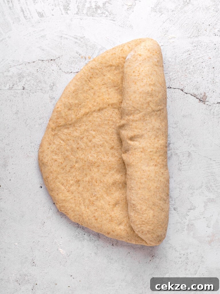Homestyle Whole Wheat Sandwich Bread Recipe for Families 8 Half rolled whole wheat bread dough on a light gray surface.