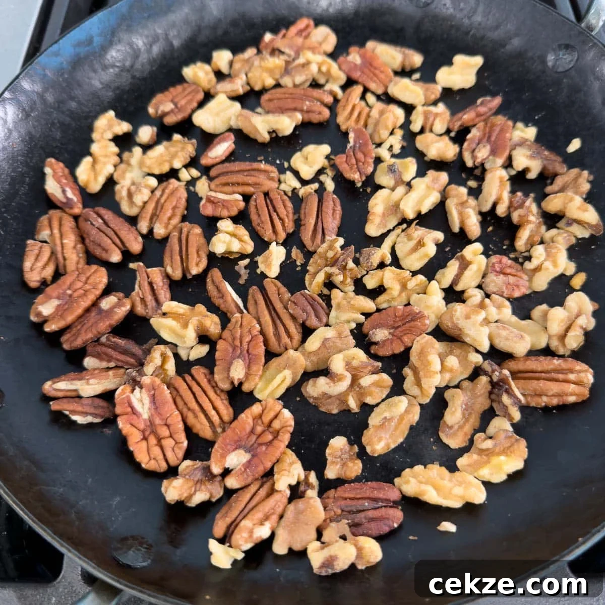Toasting walnuts and pecans in a black iron skillet.