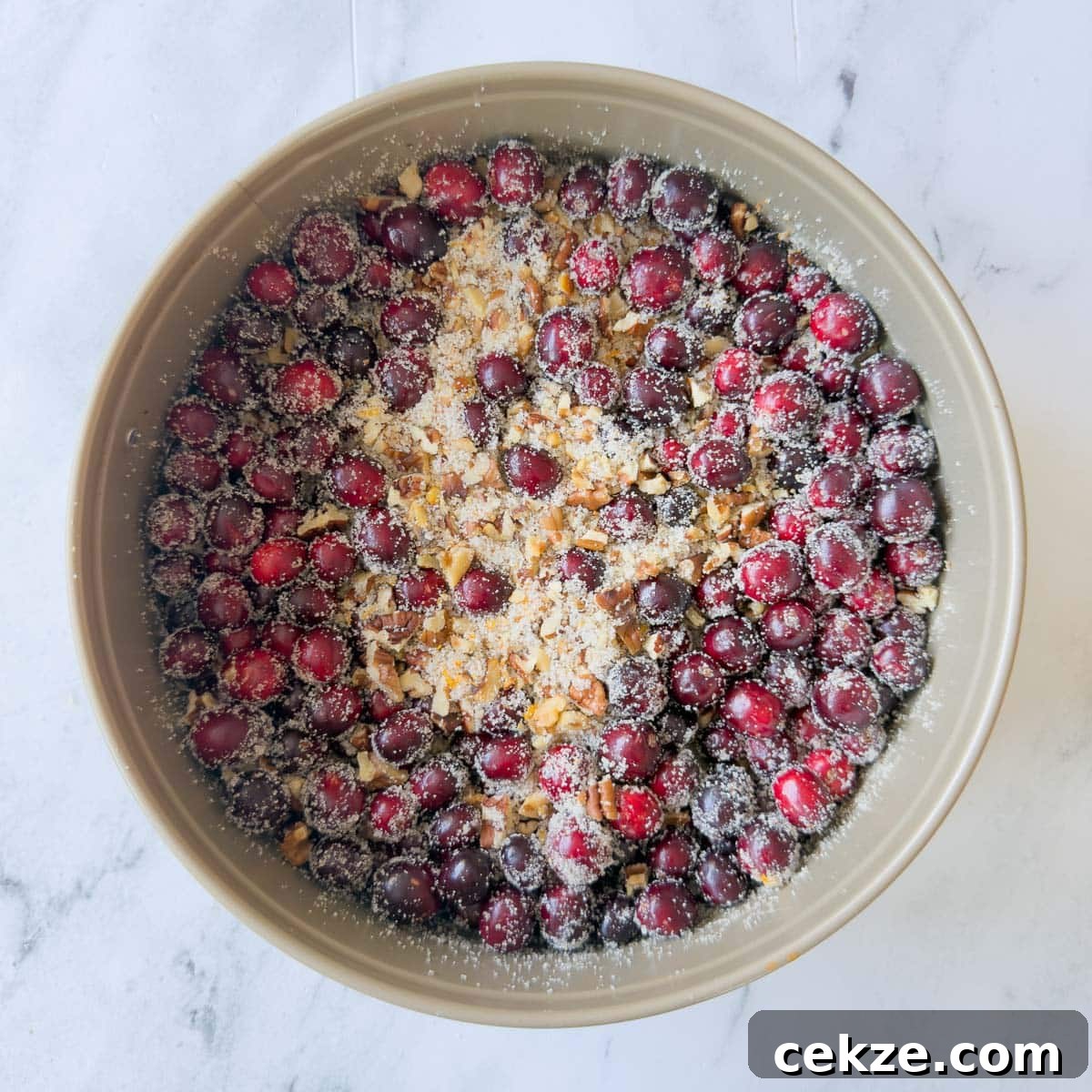 Cranberries, nuts, sugar, and orange zest mixed in a round pan.