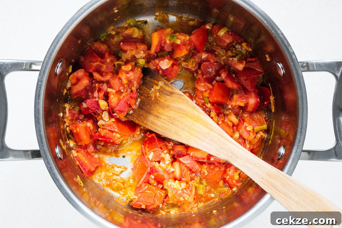 Stir-fried tomatoes, scallions and garlic viewed from above in a pot.