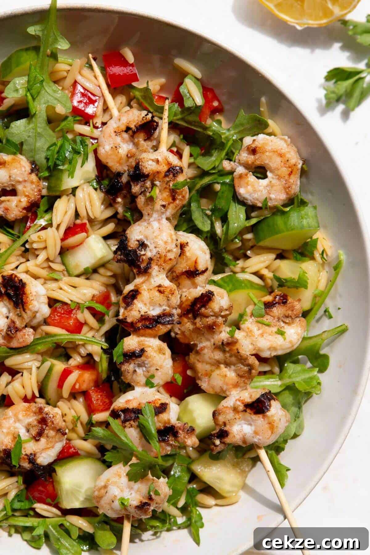 A bowl of high-protein grilled shrimp orzo salad with a balsamic dressing.