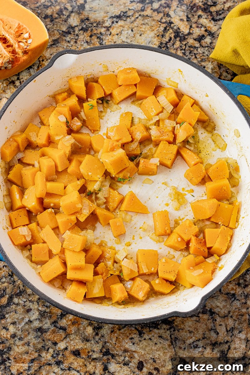 pieces of butternut squash in a large pan cooked with onions and garlic