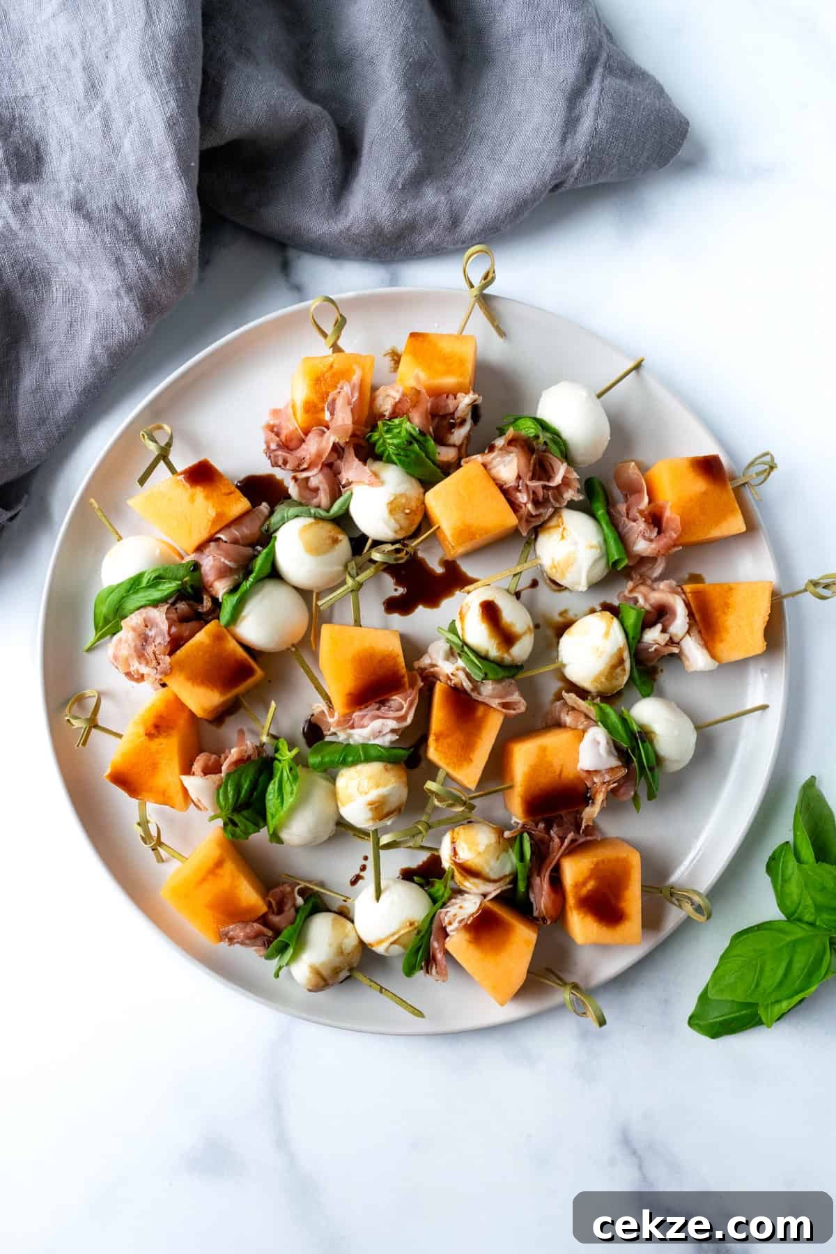 Prosciutto and Melon Skewers: Sweet-Salty Appetizer Recipe 4 Cantaloupe Appetizer Skewers on a white plate.