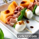 Prosciutto Melon Skewers with Balsamic Glaze on a white plate.