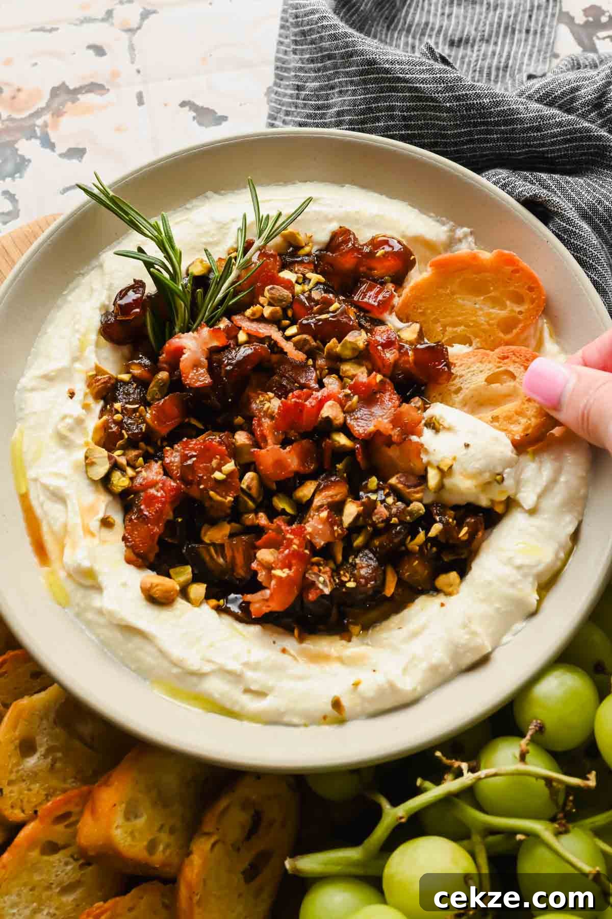 Feta, Bacon & Date Dip Recipe: Sweet Savory Party Appetizer 2 serving bowl with whipped feat cheese topped with a date, bacon, pistachio mixture garnished with rosemary.