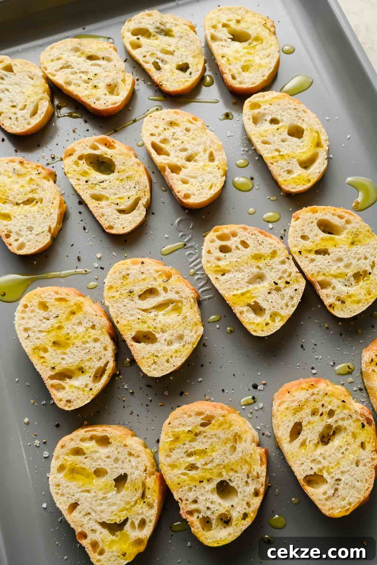 Feta, Bacon & Date Dip Recipe: Sweet Savory Party Appetizer 4 crostinis on gray sheet pan drizzled with olive oil, salt and pepper.