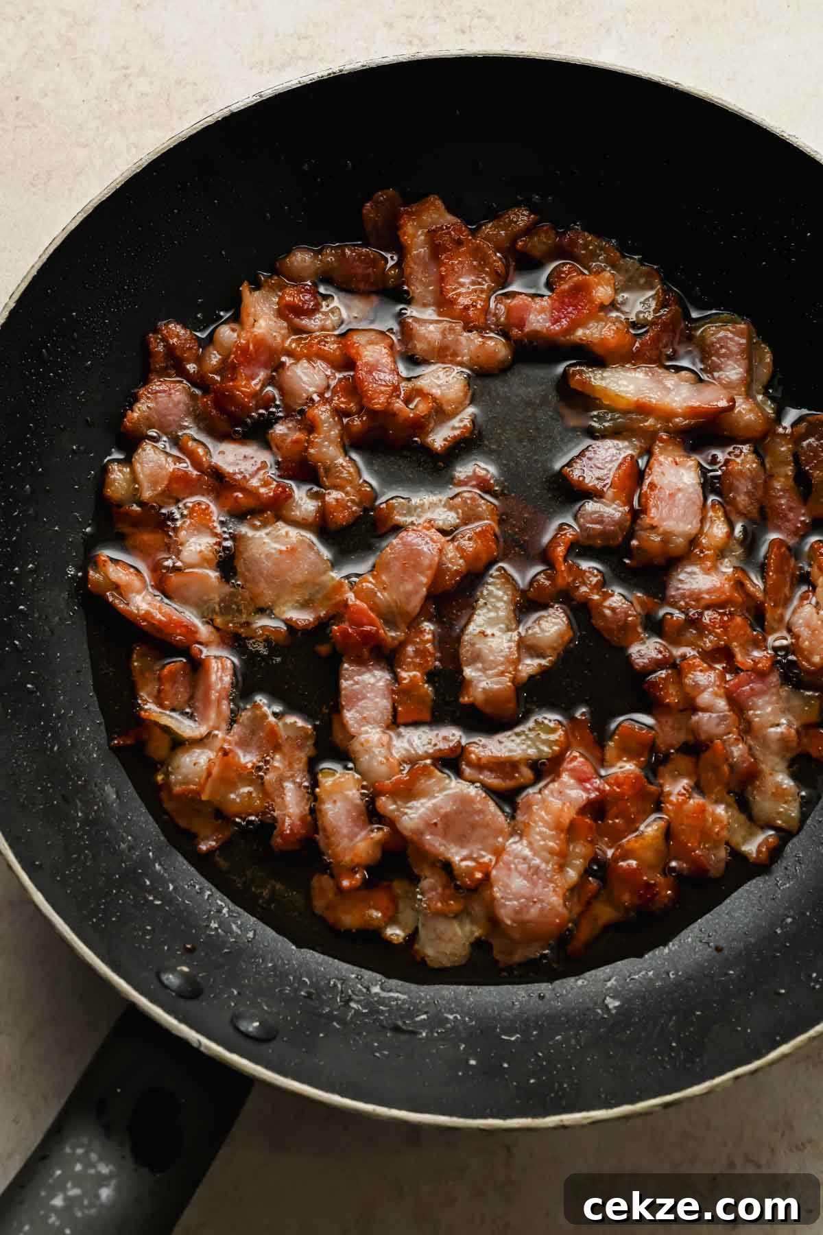 Feta, Bacon & Date Dip Recipe: Sweet Savory Party Appetizer 5 bacon bits cooking in black frying pan.