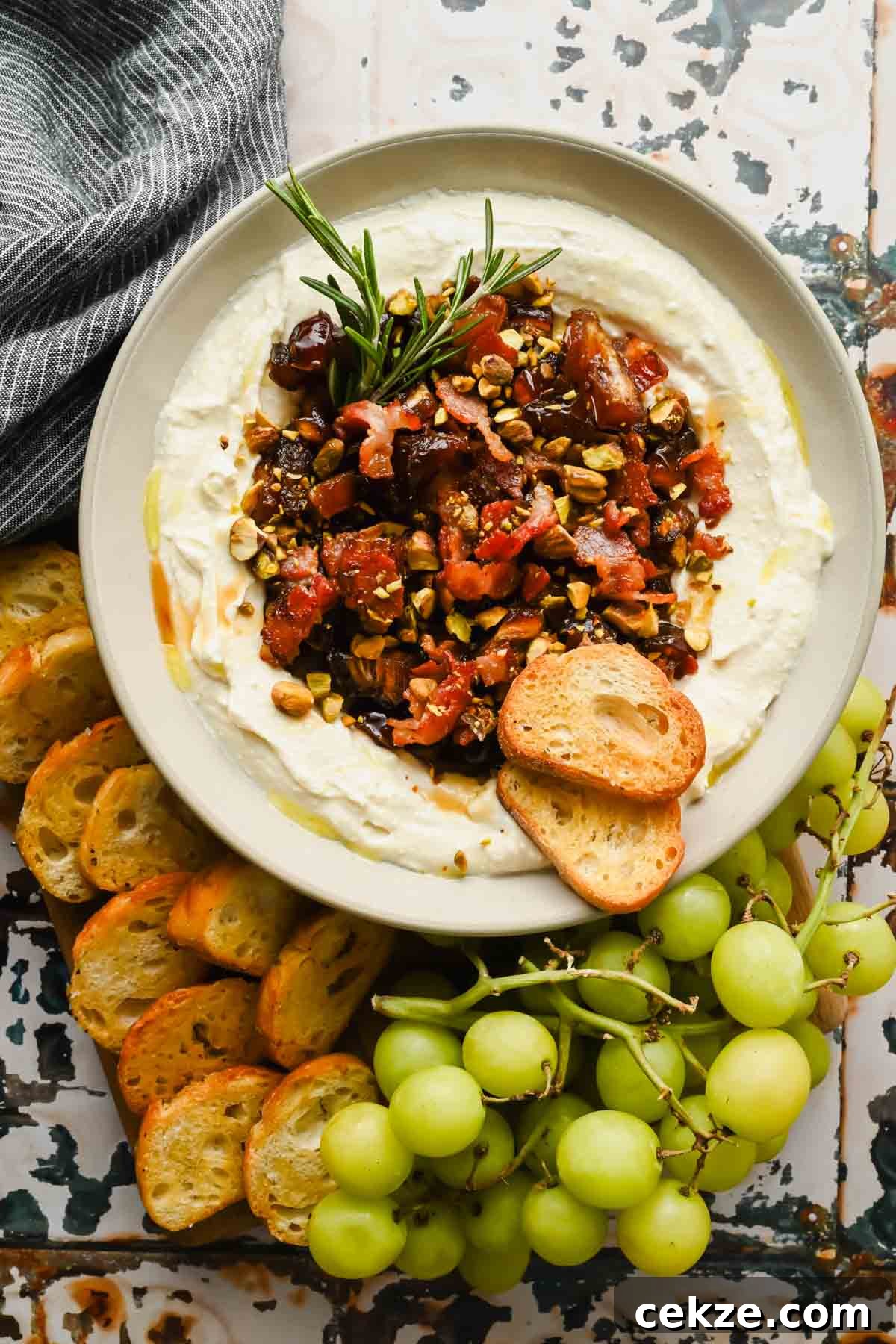 Feta, Bacon & Date Dip Recipe: Sweet Savory Party Appetizer 8 serving bowl with whipped feat cheese topped with a date, bacon, pistachio mixture garnished with rosemary.
